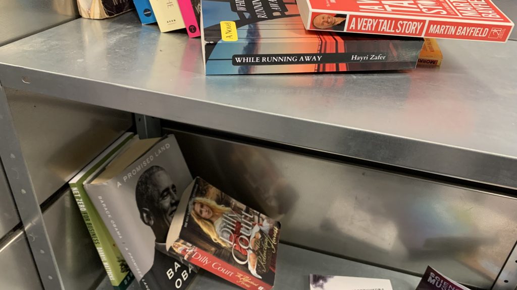 The image shows various books stacked on a metal shelf at Haggerston station's new community book area.